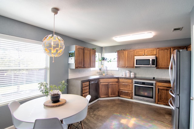 kitchen with decorative backsplash, pendant lighting, stainless steel appliances, and sink