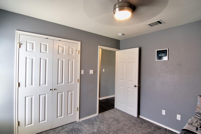 unfurnished bedroom featuring a closet, dark carpet, and ceiling fan