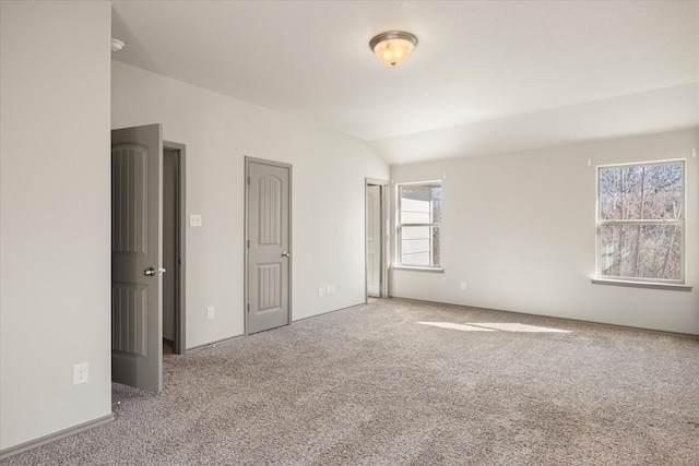 unfurnished bedroom featuring carpet and vaulted ceiling