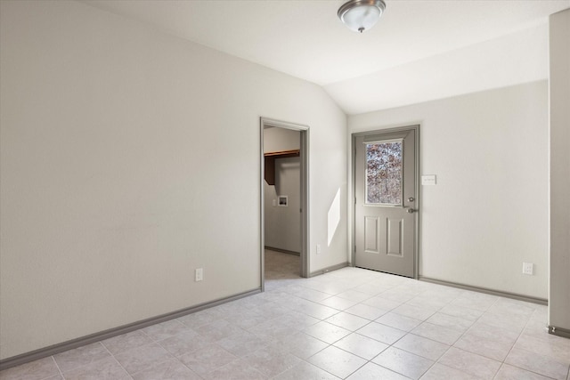 tiled spare room with vaulted ceiling