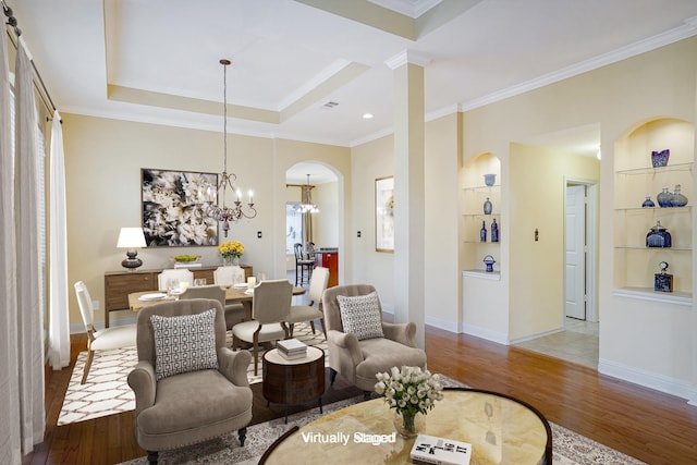 living room with light hardwood / wood-style floors, built in features, crown molding, and a chandelier