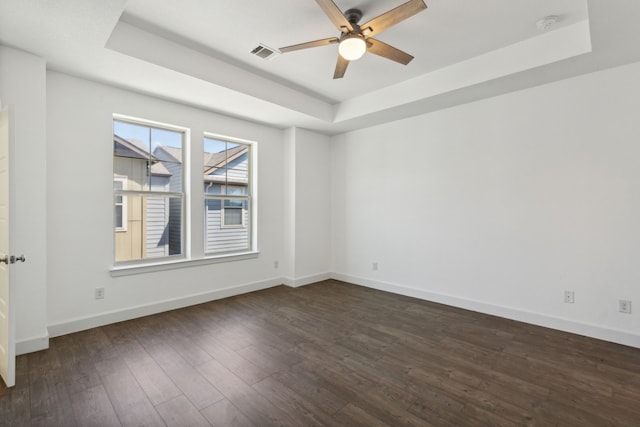 unfurnished room with dark hardwood / wood-style floors, ceiling fan, and a tray ceiling