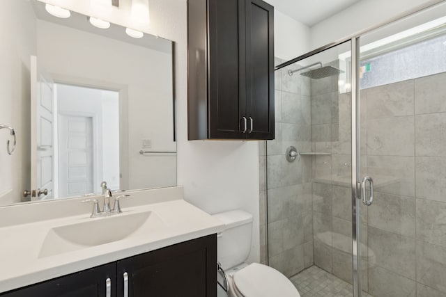 bathroom with vanity, toilet, and a shower with door