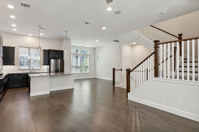 kitchen featuring decorative backsplash, appliances with stainless steel finishes, light stone counters, pendant lighting, and a center island