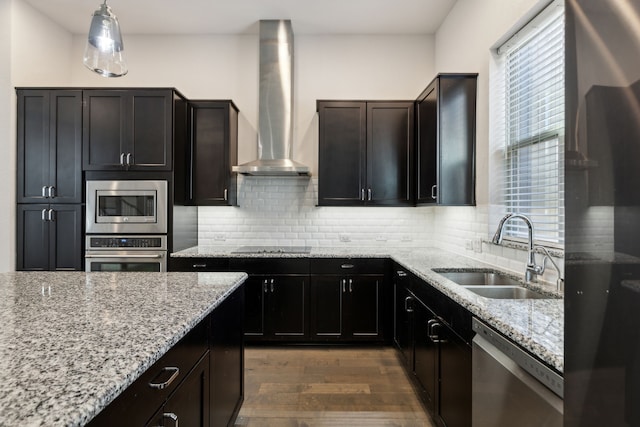 kitchen with backsplash, stainless steel appliances, sink, wall chimney range hood, and pendant lighting