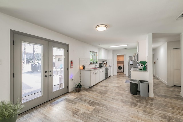 kitchen featuring french doors, washer / clothes dryer, white cabinetry, and stainless steel dishwasher