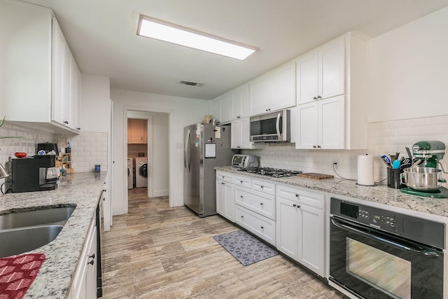 kitchen with decorative backsplash, white cabinetry, sink, and appliances with stainless steel finishes