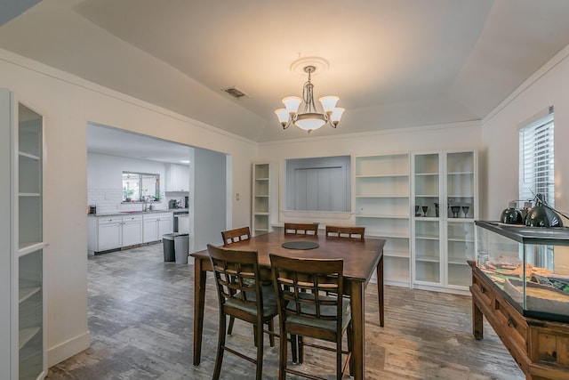 dining room with dark wood-type flooring, vaulted ceiling, and a notable chandelier