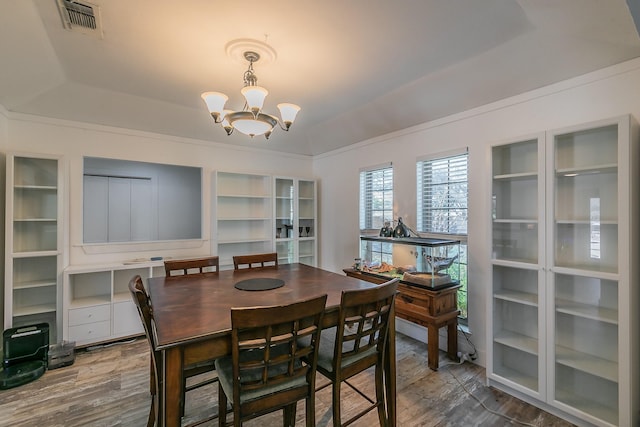 dining space featuring hardwood / wood-style floors, a notable chandelier, and a tray ceiling