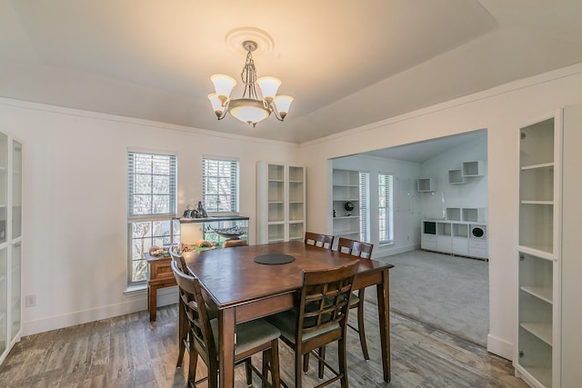 dining space featuring vaulted ceiling, hardwood / wood-style flooring, and an inviting chandelier