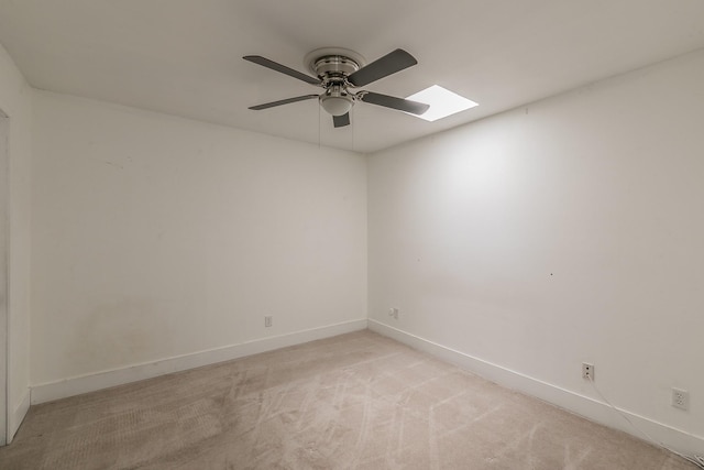 empty room with ceiling fan, light carpet, and a skylight