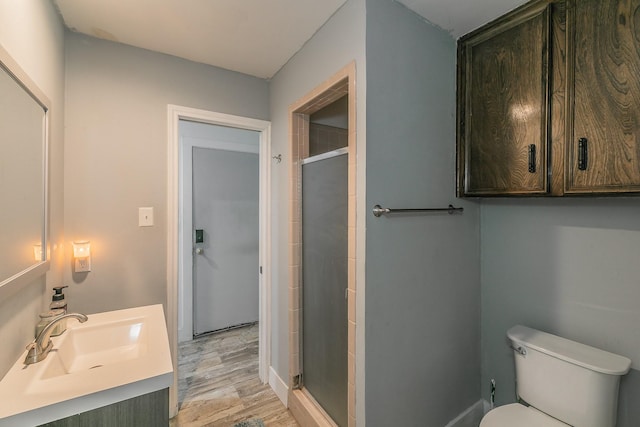 bathroom with hardwood / wood-style floors, vanity, a shower with shower door, and toilet