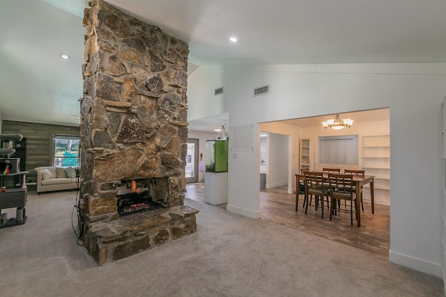 living room featuring vaulted ceiling, built in features, a fireplace, carpet floors, and a chandelier