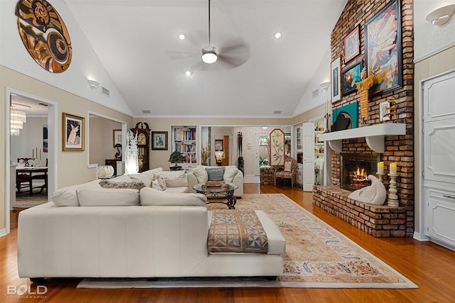 living room with a brick fireplace, wood-type flooring, high vaulted ceiling, and ceiling fan