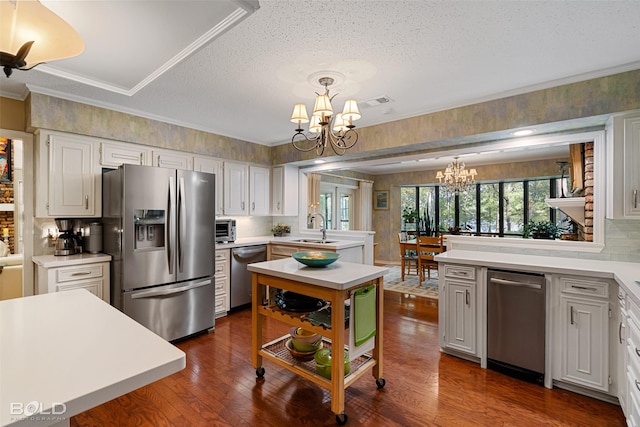 kitchen featuring white cabinetry, hanging light fixtures, an inviting chandelier, and appliances with stainless steel finishes