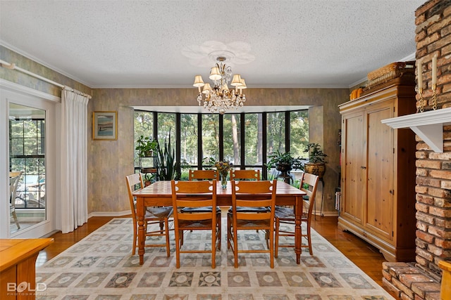 dining area with wood-type flooring, ornamental molding, a wealth of natural light, and a notable chandelier