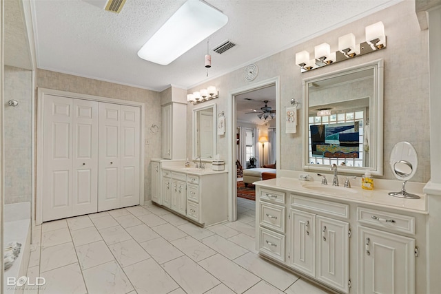 bathroom with crown molding, ceiling fan, vanity, and a textured ceiling