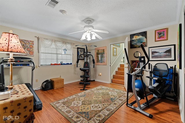 workout room featuring ornamental molding, hardwood / wood-style floors, ceiling fan, and a textured ceiling