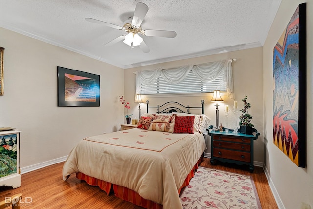 bedroom with hardwood / wood-style flooring, ceiling fan, ornamental molding, and a textured ceiling