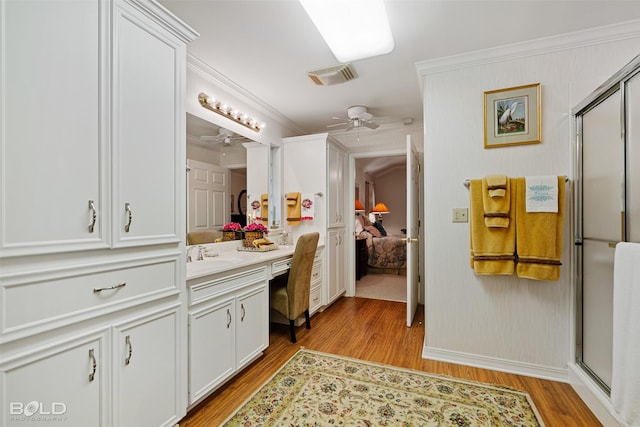 bathroom featuring a shower with shower door, crown molding, wood-type flooring, vanity, and ceiling fan