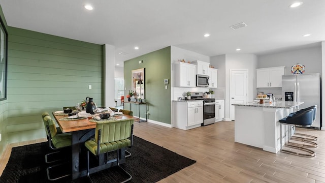 kitchen featuring a breakfast bar, appliances with stainless steel finishes, white cabinetry, and a kitchen island with sink