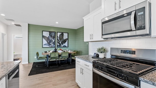 kitchen with white cabinetry, light stone countertops, and appliances with stainless steel finishes