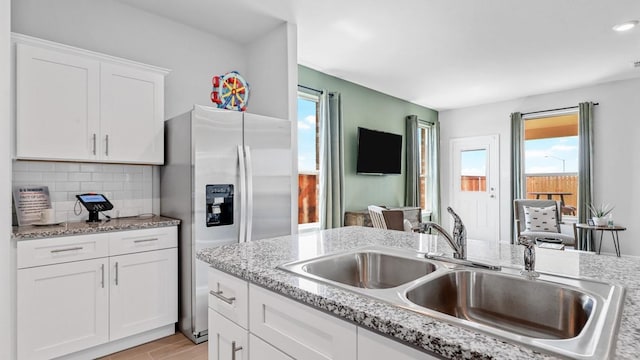 kitchen featuring tasteful backsplash, white cabinetry, plenty of natural light, and sink