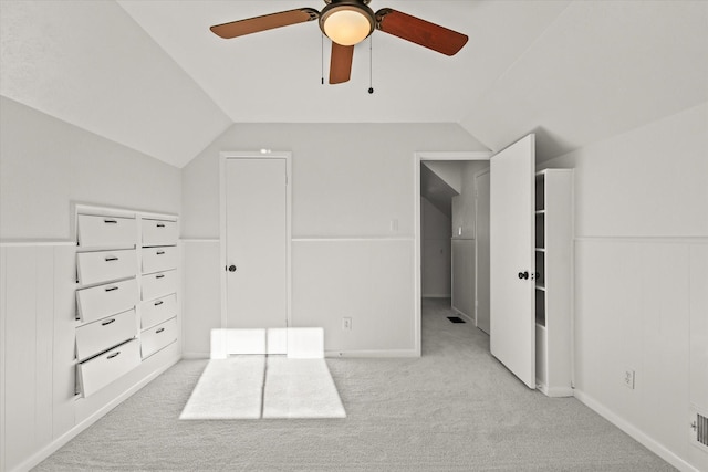 unfurnished bedroom with ceiling fan, vaulted ceiling, and light carpet