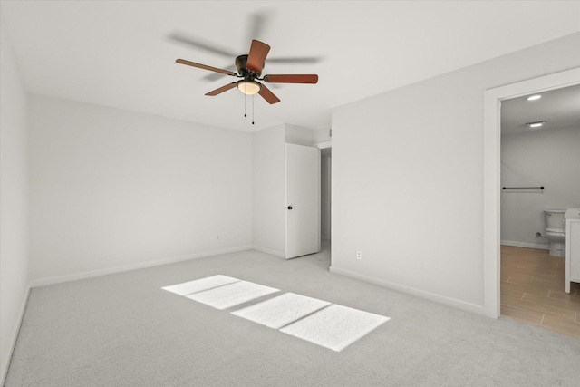 unfurnished bedroom with connected bathroom, light colored carpet, and ceiling fan