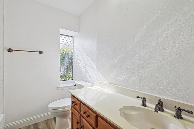 bathroom featuring hardwood / wood-style flooring, vanity, toilet, and a bathtub