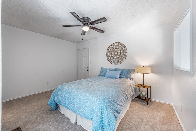 carpeted bedroom with ceiling fan and a textured ceiling