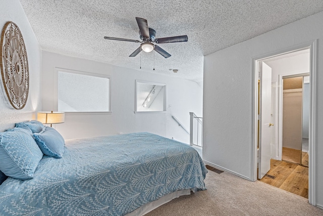 bedroom with ceiling fan, carpet flooring, and a textured ceiling