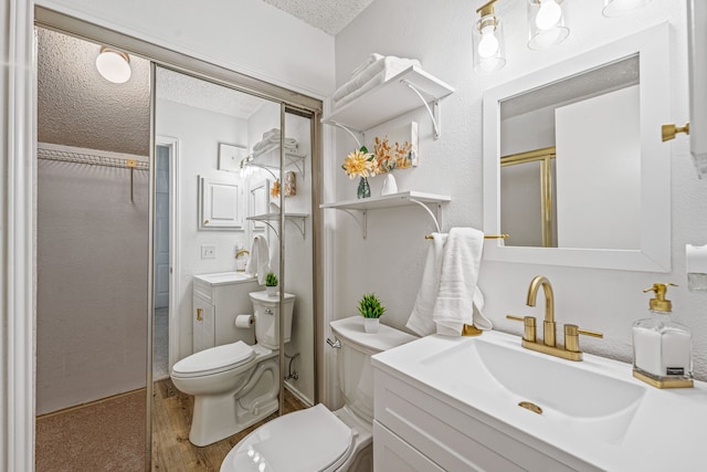 bathroom featuring vanity, toilet, a shower with door, and a textured ceiling