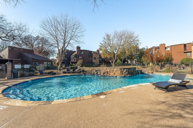 community pool featuring a residential view, a patio, and fence