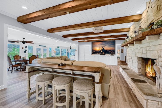 dining area featuring beam ceiling, a fireplace, light hardwood / wood-style floors, and ceiling fan