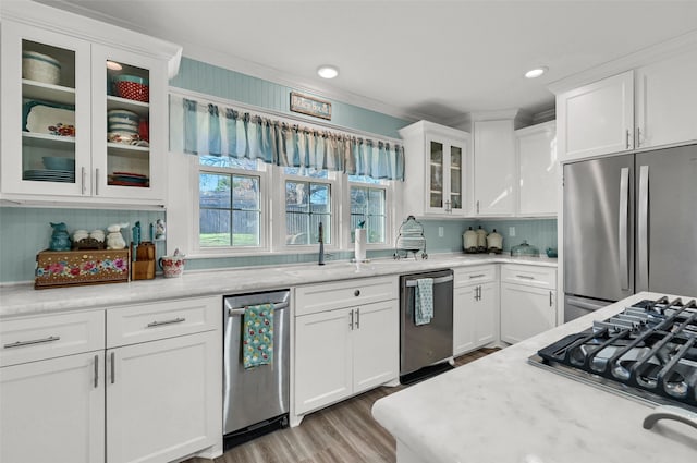 kitchen featuring sink, crown molding, white cabinetry, stainless steel appliances, and light stone counters