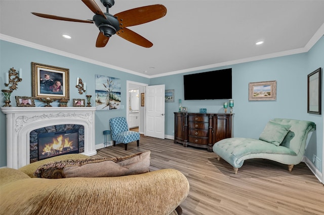 living room with light hardwood / wood-style flooring, crown molding, a fireplace, and ceiling fan