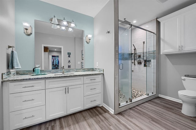 bathroom with wood-type flooring, toilet, an enclosed shower, and vanity