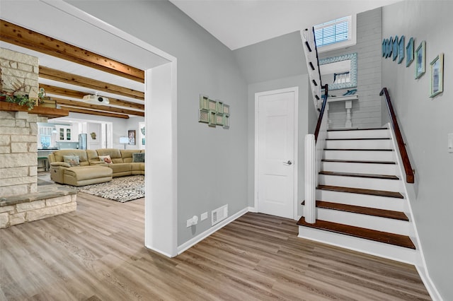 stairway featuring hardwood / wood-style floors and beam ceiling