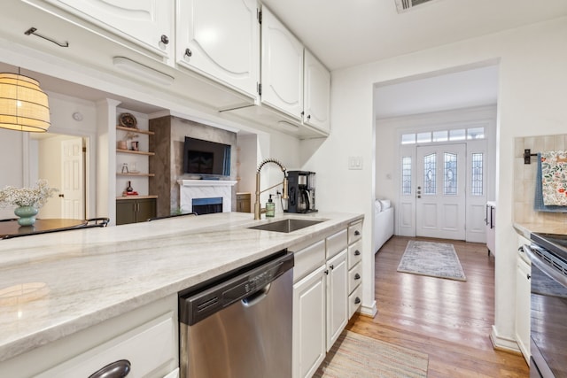 kitchen with light stone countertops, stainless steel appliances, sink, light hardwood / wood-style flooring, and white cabinets