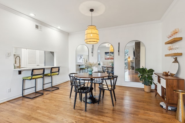 dining area with light hardwood / wood-style floors and crown molding