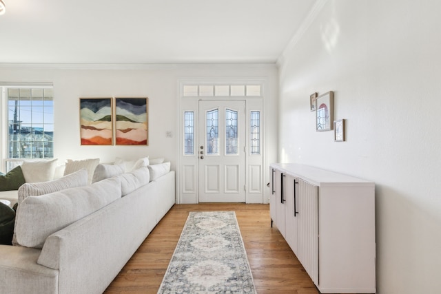 entrance foyer with plenty of natural light, ornamental molding, and light hardwood / wood-style flooring