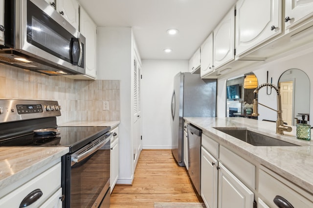 kitchen featuring light stone counters, sink, white cabinets, and stainless steel appliances