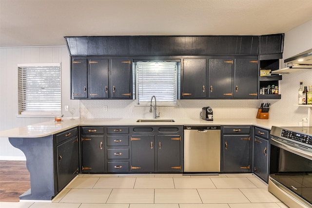 kitchen with kitchen peninsula, appliances with stainless steel finishes, a kitchen bar, tasteful backsplash, and sink