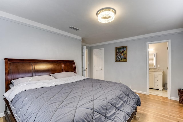 bedroom with light wood-type flooring and connected bathroom