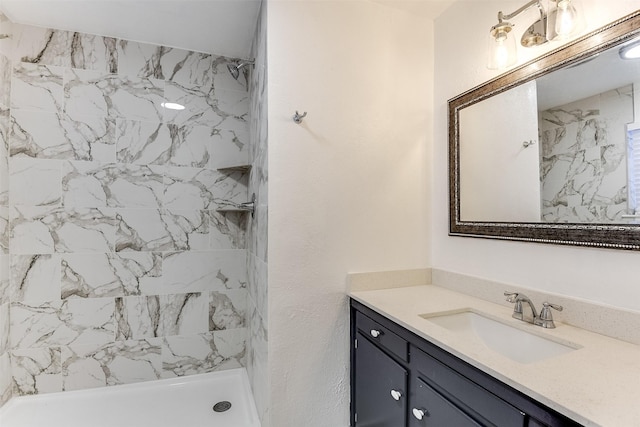 bathroom with tiled shower and vanity