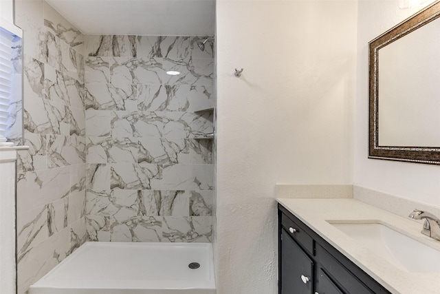 bathroom with a tile shower and vanity