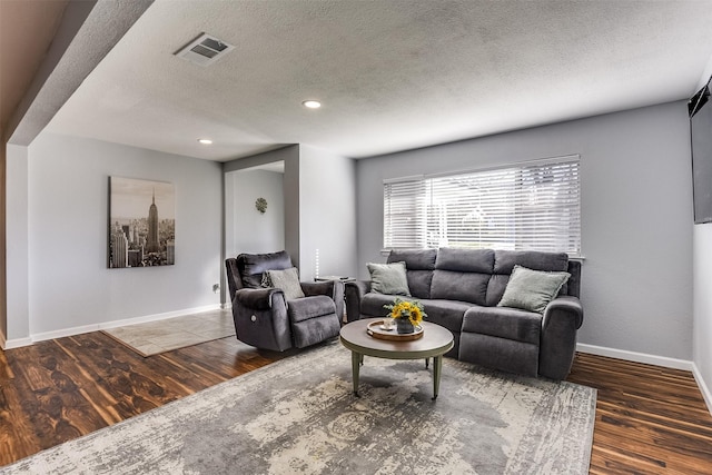 living room featuring dark wood-type flooring and a textured ceiling