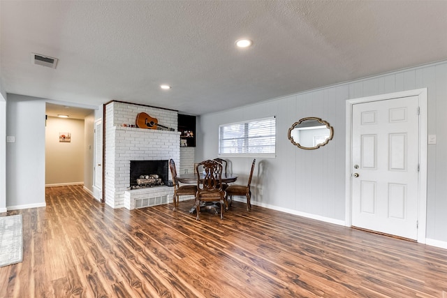 dining room with a fireplace, a textured ceiling, and dark hardwood / wood-style floors