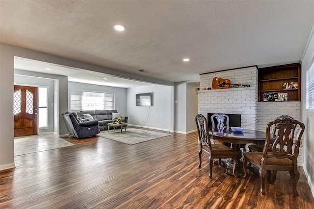 dining room with a fireplace, a textured ceiling, and dark hardwood / wood-style flooring